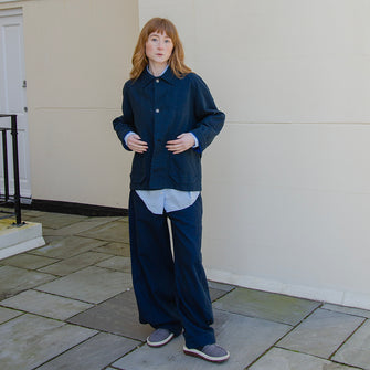 Woman wearing cotton workwear trousers with button details at ankle to adjust width.