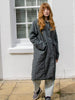Model wears grey spring coat made from crinkle cotton and linen fabric. Seam details, patch pockets and button front.