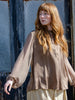 Woman wearing coffee coloured fluid silk shirt with sheer sleeves. Featuring half button front, gathered collar and elastic cuffs.