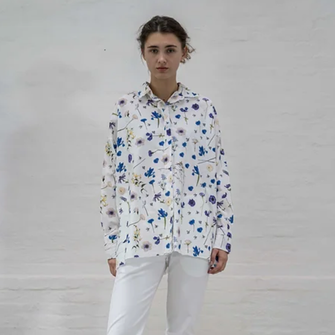 Woman wearing oversized white cotton shirt with floral print. Raw hem finishing and button through front.